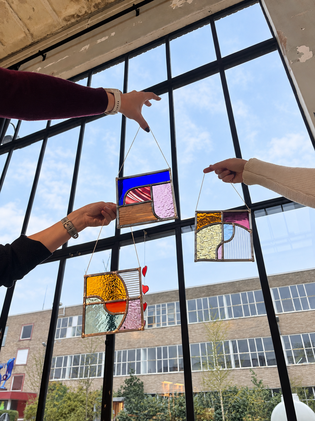 Deelnemers houden hun glas-in-loodpanelen tegen het licht